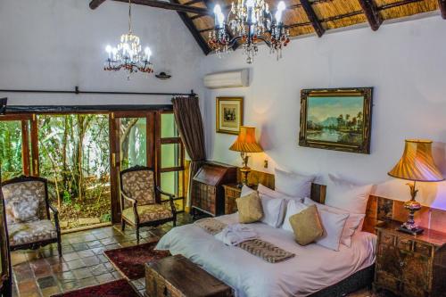 a living room with a bed and chairs and a chandelier at Kedar Heritage Lodge, Conference Centre & Spa in Phokeng