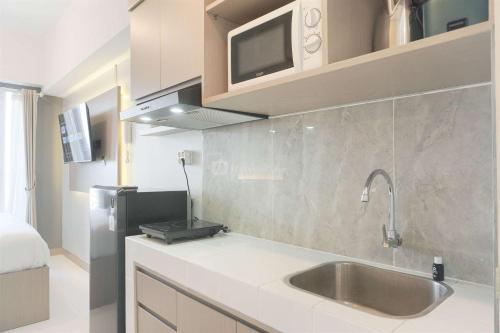 eine Küche mit Spüle und Mikrowelle in der Unterkunft Comfort Studio Room Tokyo Riverside PIK 2 Apartment By Travelio in Rawalembang