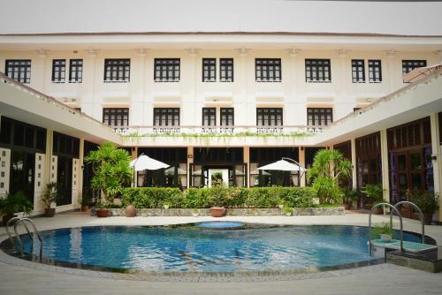 a large building with a swimming pool in front of it at Villa Hue Hotel in Hue