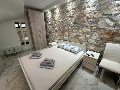 a bedroom with a stone wall and a bed with towels at Villa Stephanie in Hanioti