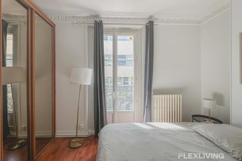 une chambre avec un lit et une grande fenêtre dans l'établissement Flexliving - room - Lindet, à Paris