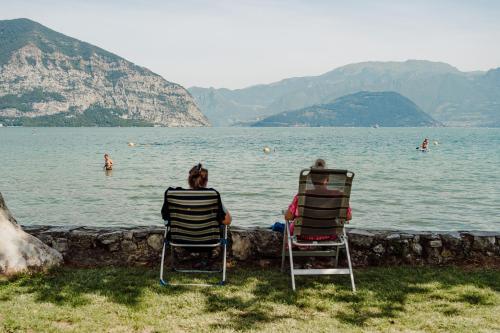 two people sitting in chairs watching people in the water at Camping Del Sole Village in Iseo