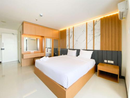 a bedroom with a large white bed and a mirror at Cozy Living Studio (No Kitchen) at Sentraland Semarang Apartment By Travelio in Semarang