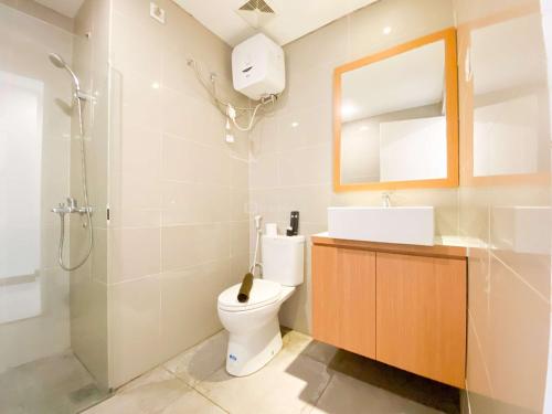 a bathroom with a toilet and a sink and a mirror at Cozy Living Studio (No Kitchen) at Sentraland Semarang Apartment By Travelio in Semarang