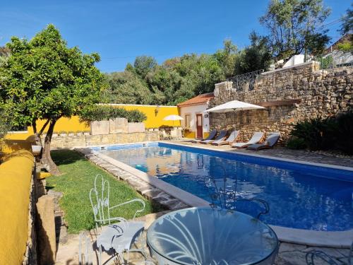 a swimming pool with chairs and a house at Casinha da Pena - Tomar (Pedreira) in Tomar
