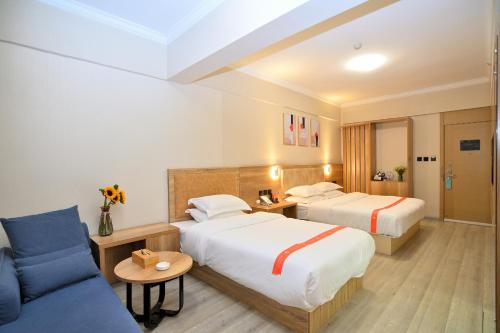 a hotel room with two beds and a couch at Yilong Yitang Hotel Kunming Railway Station Joy City Center in Kunming