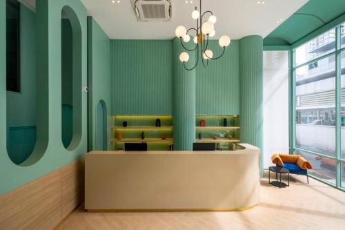 a waiting room with green walls and a desk and a chandelier at Myhotel Cmyk@Ratchada in Bangkok