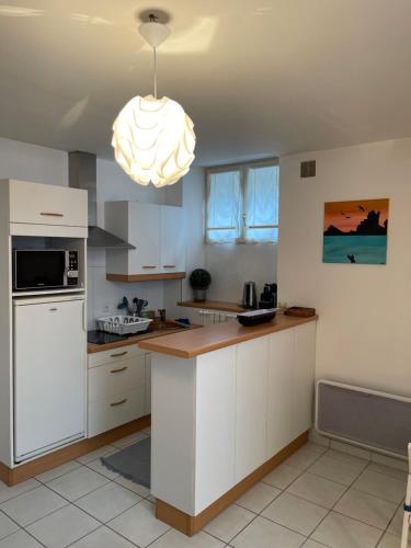 une cuisine avec des armoires blanches et un lustre dans l'établissement Appartement BIARRITZ, à Biarritz