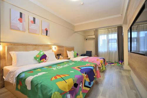 a bedroom with two beds and a tv in it at Yilong Yitang Hotel Kunming Railway Station Joy City Center in Kunming