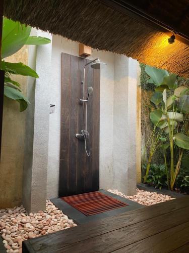 a bathroom with a shower with a wooden door at Villa Purnamasari in Ubud