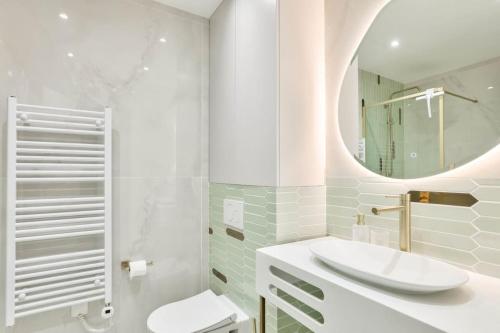une salle de bain blanche avec un lavabo et un miroir dans l'établissement Terrace Getaway - Le Marais - with AC, à Paris