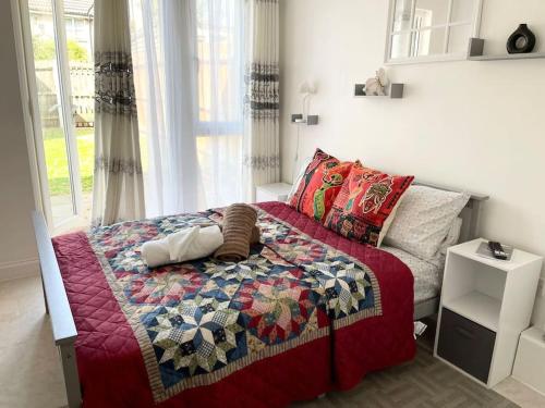 a bed with a quilt on it in a bedroom at Crescent 2 Bedroom Apartment in Goodmayes