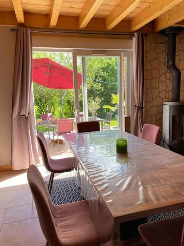 - une table à manger avec des chaises et un parasol dans l'établissement Charmante maison en bois 8 pers, à Fontenu