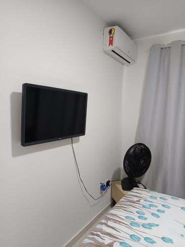 TV de pantalla plana colgada en una pared junto a la cama en Portinari 2, en Rio das Ostras