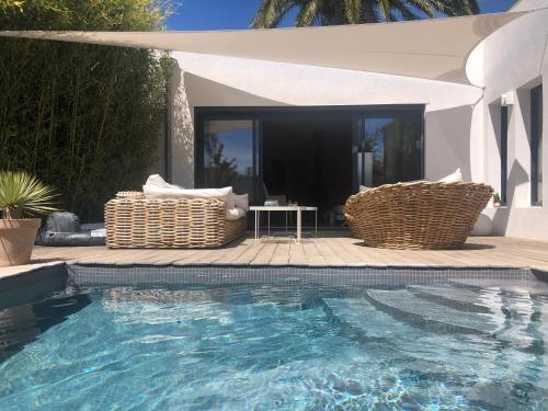 - une piscine avec 2 chaises en osier à côté d'une maison dans l'établissement Seasun, à Saint-Cyr-sur-Mer