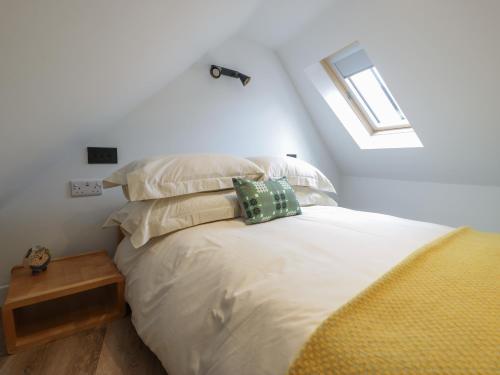 a bedroom with a bed with pillows and a window at Llofft Penwaig The Herring Loft in Cemaes Bay