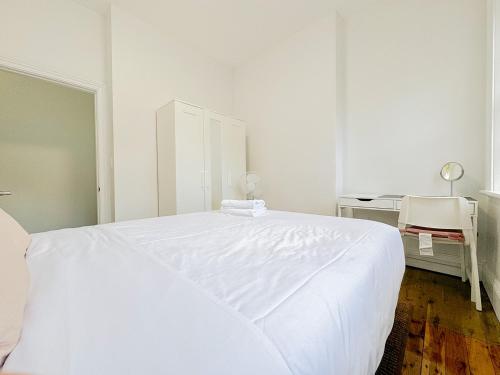 a white bedroom with a large white bed and a desk at Millers Point Waterview in Sydney