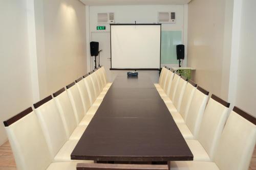 a conference room with a long table and white chairs at Casablanca Suites Near Airport in Legazpi
