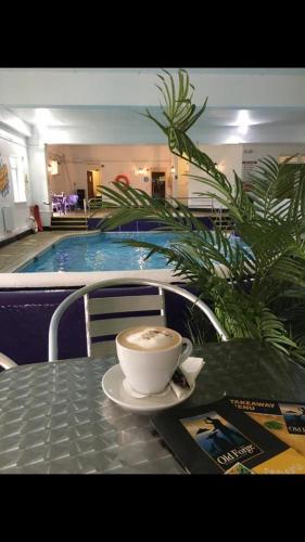 a cup of coffee sitting on a table in front of a pool at Tolpedn Cottage in Gulval