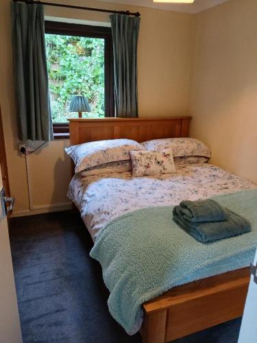 a bed in a bedroom with a window and a bedspread at Tolpedn Cottage in Gulval
