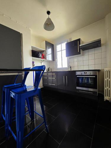 une cuisine avec un tabouret bleu et une cuisinière dans l'établissement APPARTEMENT T2 Spacieux et lumineux, à Gennevilliers