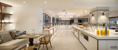 a large kitchen with a long counter and a table at Ilunion Caleta Park in Sant Feliu de Guixols