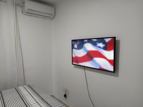 a tv on a wall with an american flag on it at Portinari 2 in Rio das Ostras