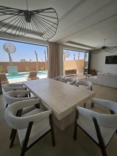 a dining room with a large table and chairs at Domaine de Kali, villa 2 au calme, piscine privée in Marrakech