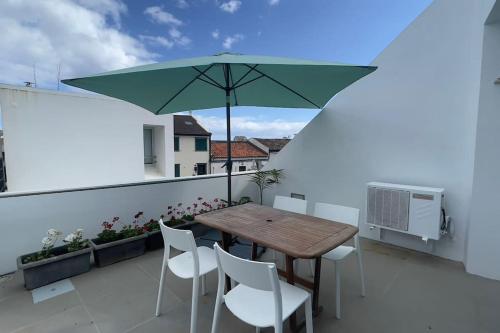 a table and chairs on a balcony with an umbrella at Casa do Mar North in Ponta Delgada