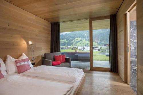 a bedroom with a bed and a couch and a window at Smaragdresort Top 3.2 Happy Alps in Bramberg am Wildkogel