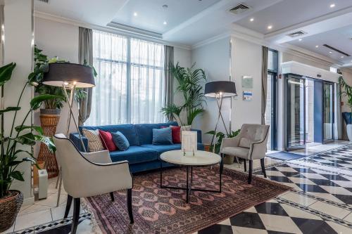 a living room with a blue couch and chairs at Queen's Court Hotel & Residence in Budapest