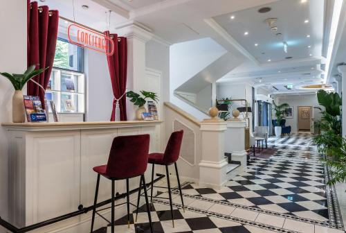 a bar in a salon with red stools at Queen's Court Hotel & Residence in Budapest
