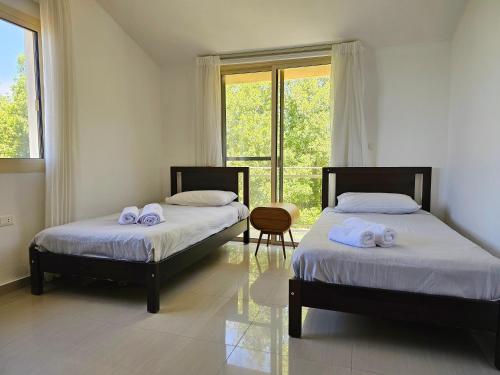 two beds in a room with a window at Beit Mema in Aḑ Ḑahr