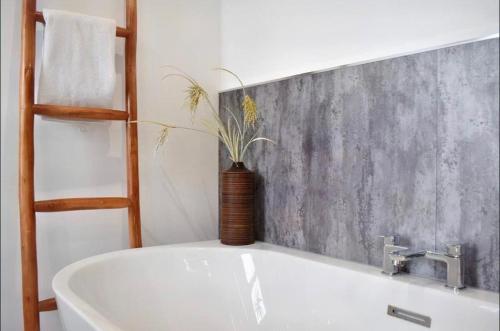a bathroom with a white tub and a vase with a plant at Autumn Loft Wyndale Living Malvern Hills in Great Malvern