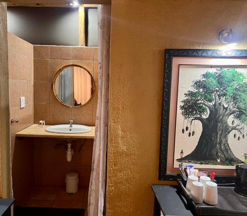 a bathroom with a sink and a painting of a tree at Lapa Lange Game Lodge in Mariental