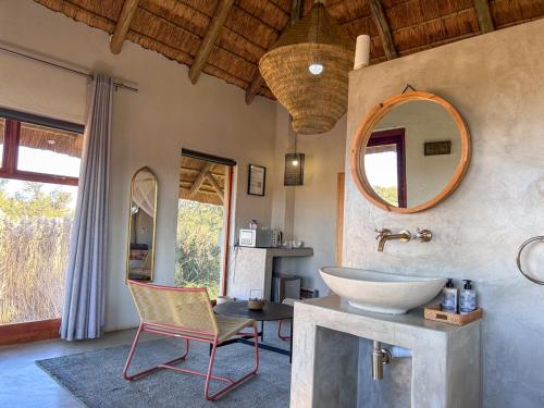 a bathroom with a sink and a chair and a mirror at Tzamenkomst River Lodge in Colesberg