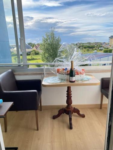 une table avec une bouteille de champagne dans une pièce avec une fenêtre dans l'établissement Studio avec loggia, classé 2 étoiles, situé sur le port, à Courseulles-sur-Mer