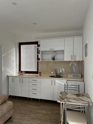 a kitchen with white cabinets and a sink and a table at Villa Marina in Ohrid