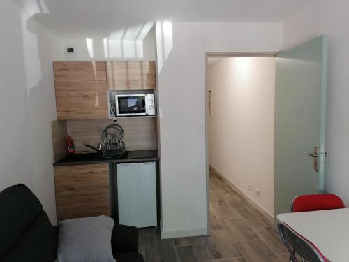 une petite cuisine avec un évier et un micro-ondes dans l'établissement Logement bord de y, à Les Sables-dʼOlonne