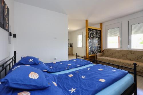 a bedroom with two beds with blue sheets and a couch at Harmonija in Palić