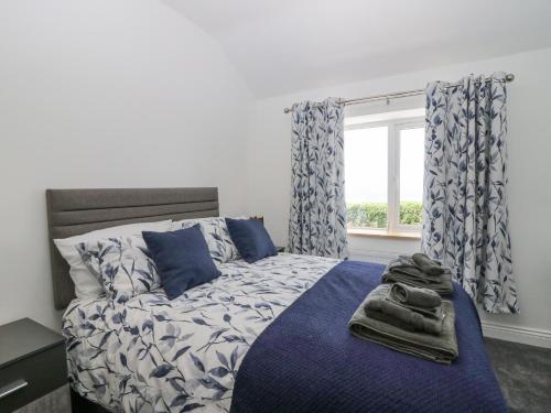a bedroom with a bed with blue sheets and a window at Victroneen Cottage in Whitehaven