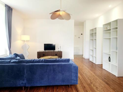 a living room with a blue couch and a television at Le Jardin d'Eden in Ay-sur-Moselle