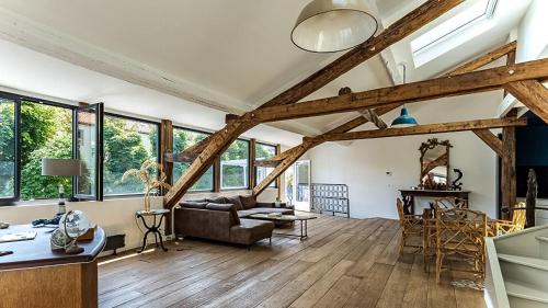 un salon avec poutres apparentes et un canapé et des tables dans l'établissement Loft 92 - Avec belle terrasse proche de Paris, à Ville-dʼAvray