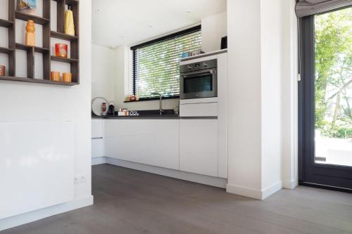 Una cocina con gabinetes blancos y una ventana. en Villa Zon & Duin, en Egmond aan den Hoef