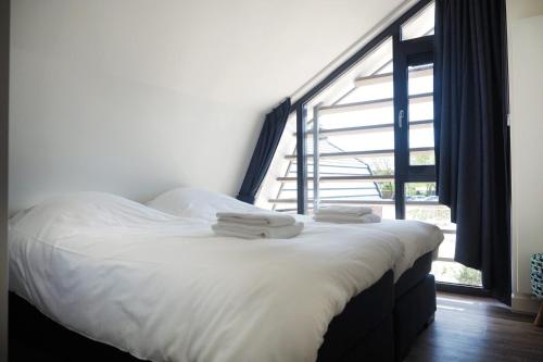 una cama en una habitación con una ventana grande en Villa Zon & Duin, en Egmond aan den Hoef