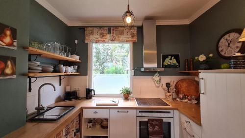 a kitchen with a sink and a clock on the wall at Ferienhaus in Caputh mit Grill, Garten und Terrasse in Schwielowsee