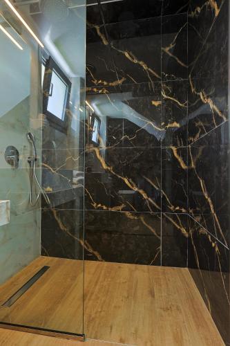 a bathroom with a shower with a black marble wall at Dream Olympus Mare Seaside Pool Villas in Olympic Beach