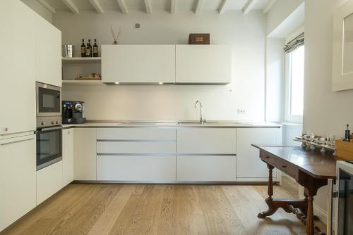 a kitchen with white cabinets and a wooden table at Suite Greve in Chianti in Greve in Chianti