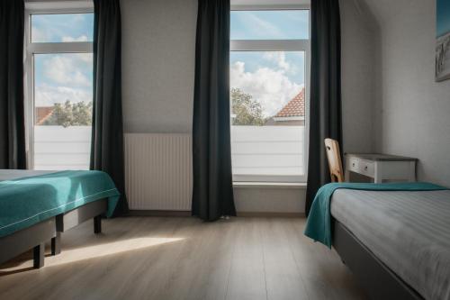 a bedroom with two beds and a large window at Hotel Groede in Groede