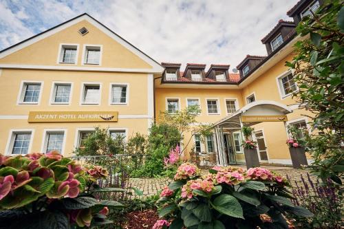 a large yellow building with flowers in front of it at AKZENT Hotel Aufkirchen in Aufkirchen